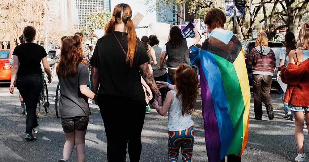 Two adults and two children walk hand in hand with Pride flag, same-sex couples are not included in the Ireland IVF scheme