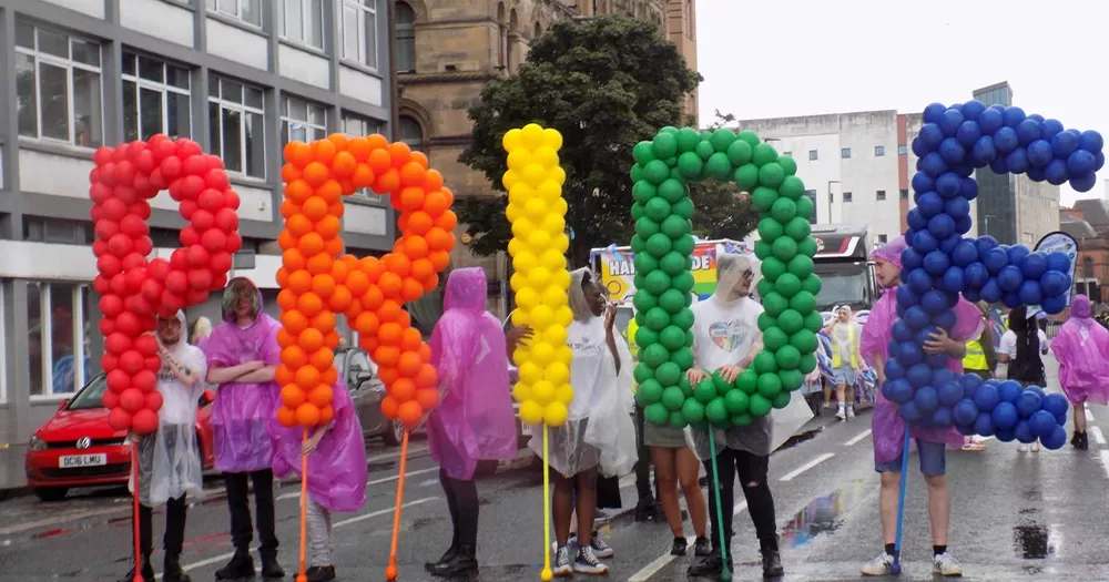 Participants at Belfast Pride 2023, where a homophobic preacher was attending. The participants are holding rainbow Pride balloons.