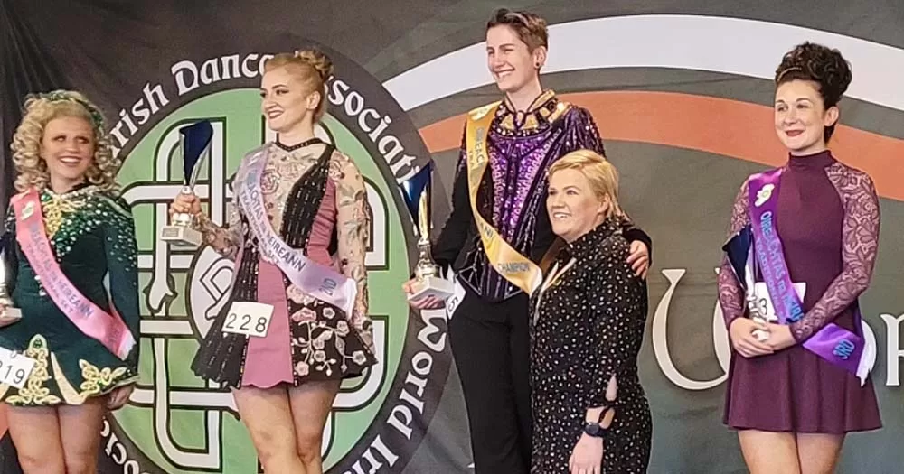 Irish dancer stands on podium next to other competitors