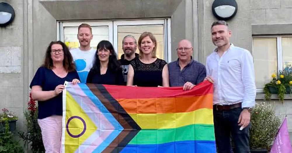 The image shows the Donegal LGBTQ+ Heritage Project team holding a progressive Pride flag.