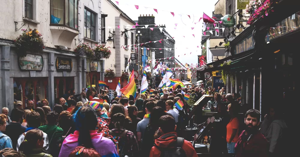 This article is about Galway Pride 2023. In the photo, a street in Galway full of people celebrating Pride with rainbow flags.