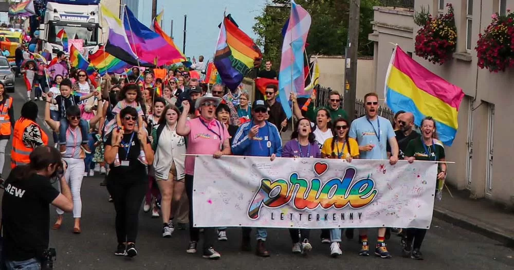 Crowd of people march with Pride flags at the first ever Letterkenny Pride parade