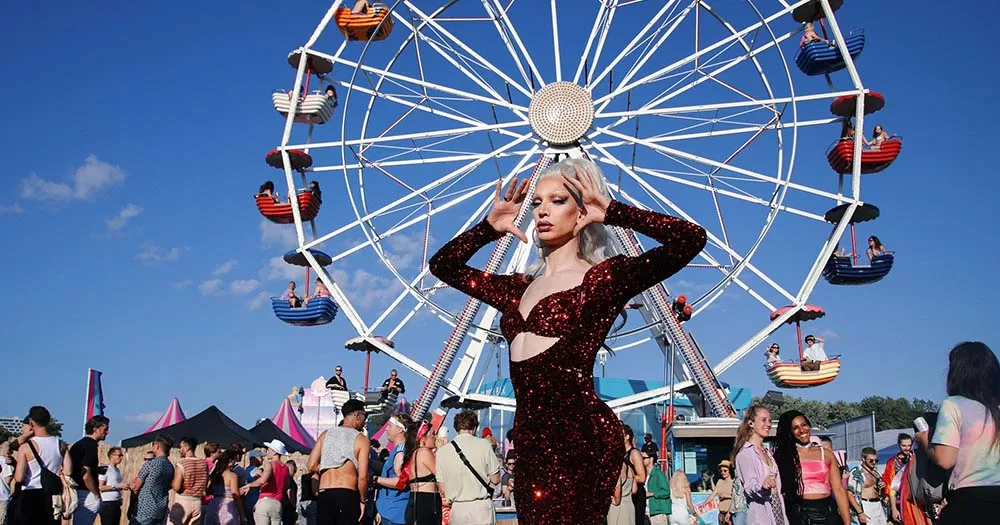 drag queen poses in front of ferris wheel at the milkshake festival