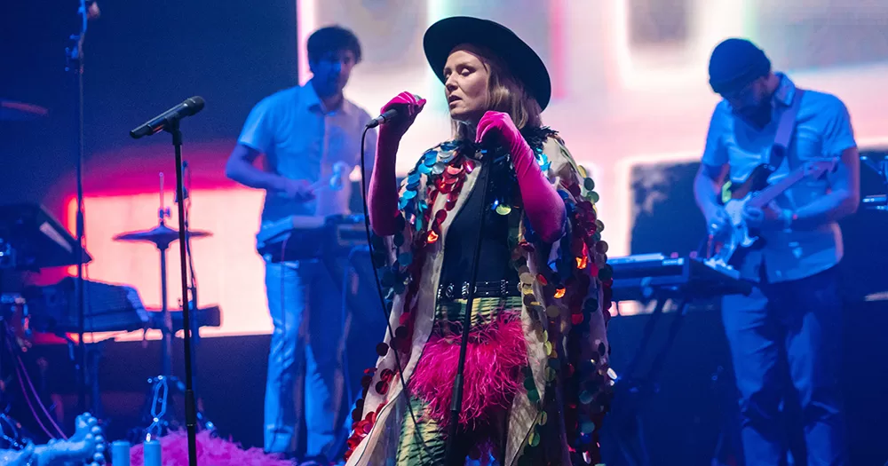 Róisín Murphy performing on stage. She wears an extravagant outfit and holds a microphone.