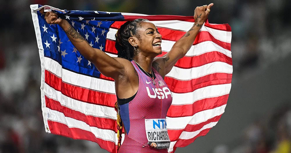 Sha'Carri Richardson holding a US flag as she celebrates her World Championships win.