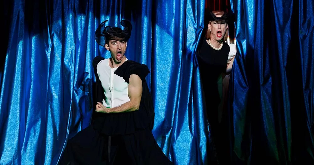 An image from Only an Octave Apart of two performers on stage in front of a blue curtain.