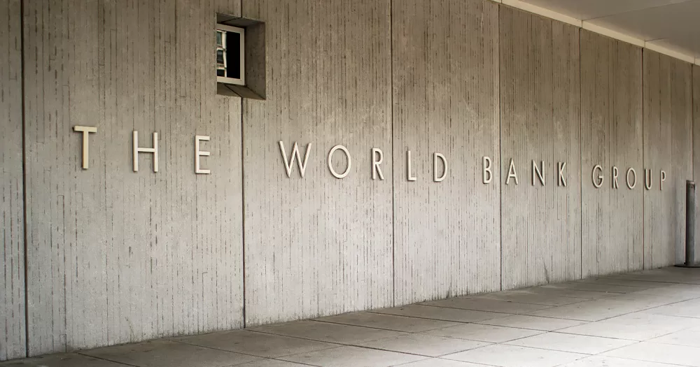 This article is about the World Bank cutting funds to Uganda. In the photo, a grey wall with the World Bank Group sign on it.