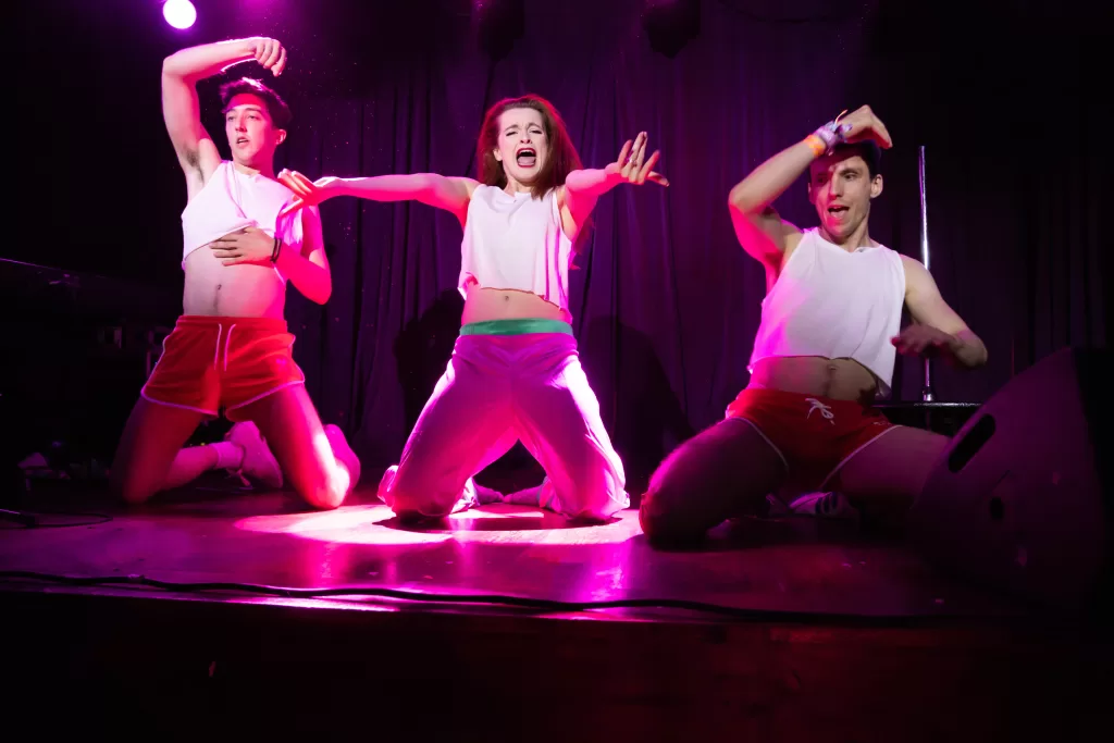 Photo from the Candlelight Cabaret featuring three dancers dressed in white on a stage.