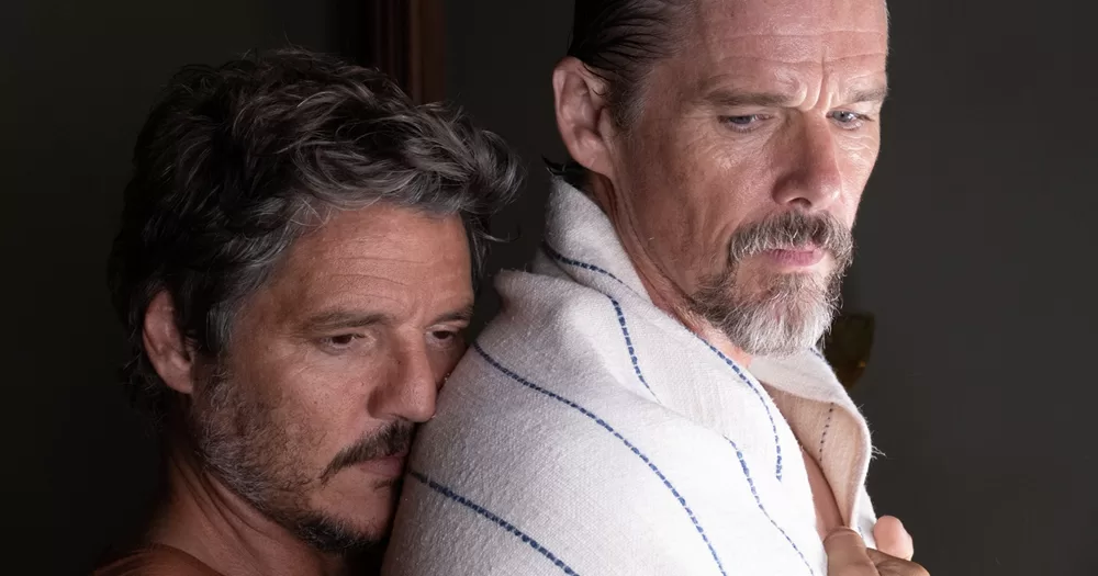 Pedro Pascal and Ethan Hawke starring in gay western short Strange Way of Life, with Pascal hugging Hawke from behind while the latter has a towel on his shoulders.