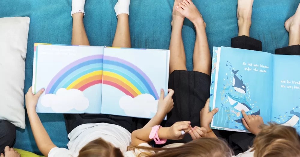 This article is about a books campaign launched in response to anti-LGBTQ+ protests. In the photo, children reading books, one showing a rainbow and another the sea with whales.