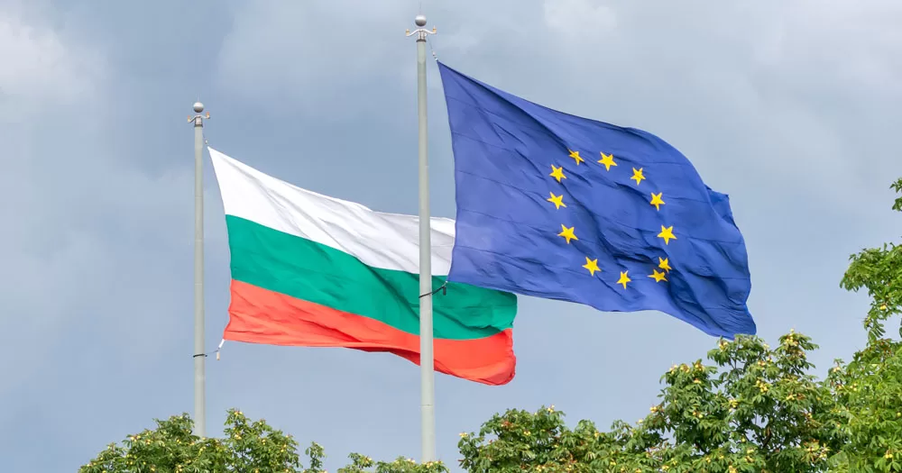 The European Court of Human Rights has ruled that Bulgaria must recognise same-sex relationships. The image shows the Bulgarian and European flags flying at the top of flag poles over trees.