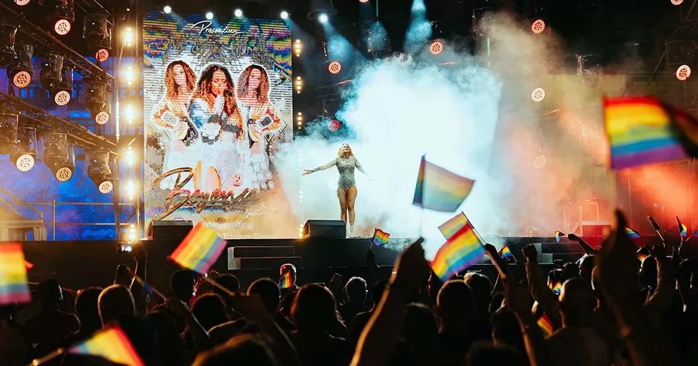 Crowd of people stand in front of stage waving Pride flags during EuroPride 2023 in Malta