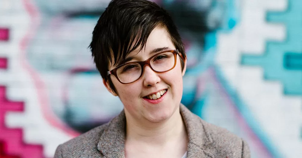 The image shows journalist Lyra McKee after she was posthumously honoured by the One World Youth Summit. In the image, Lyra is looking directly at the camera with her head tilted slightly to the left. She has short cropped hair and glasses.