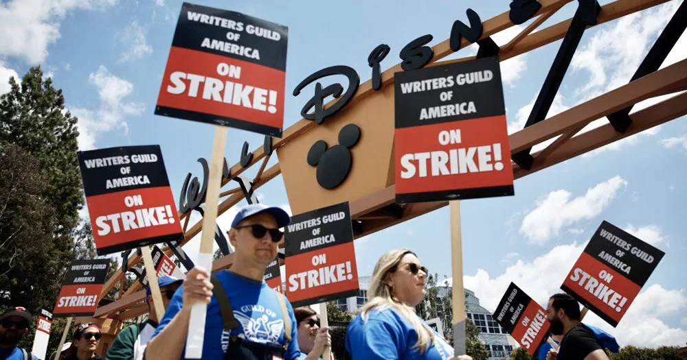 Writers on strike, who have now reached a deal with studios, carrying signs that read "Writers Guild of America on strike!".
