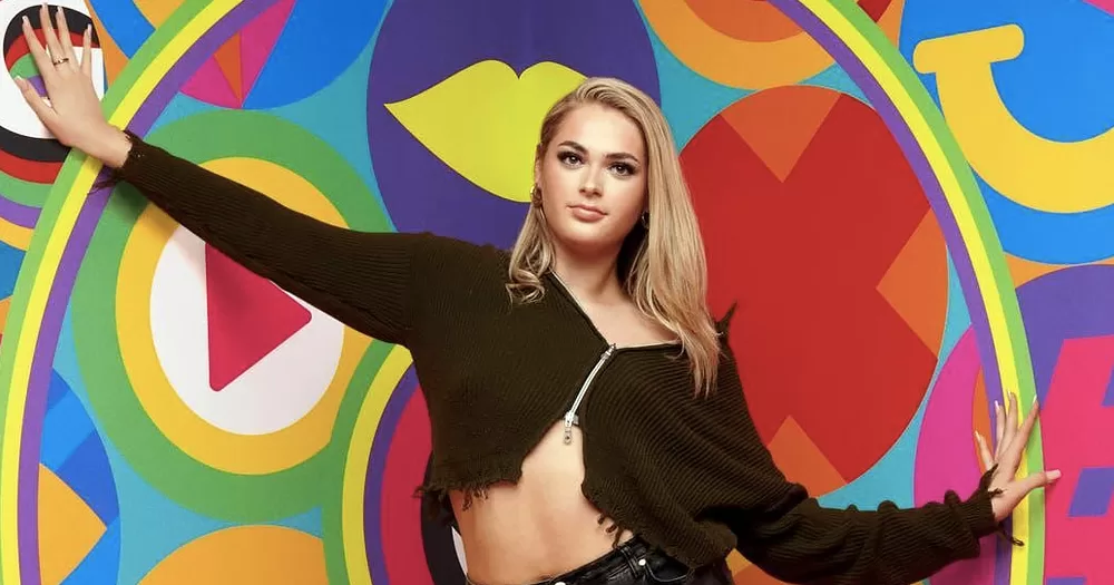 Big Brother contestant Hallie, who came out as trans, posing in front of a colourful background.