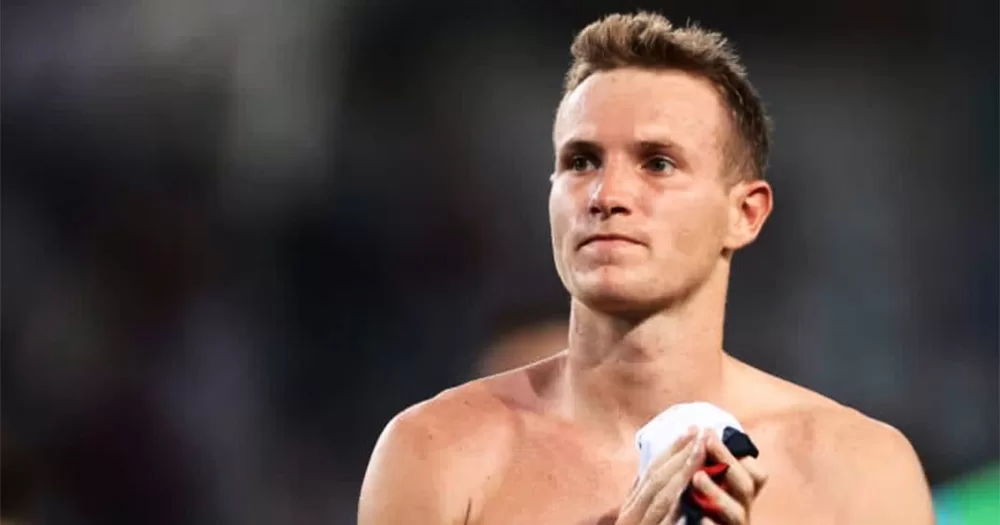 Gay footballer Jakub Jankto photographed from the shoulders up. He is shirtless and looks into the distance while holding a jersey in his hands.