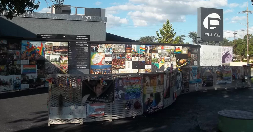 The exterior of Pulse nightclub following a deadly shooting. The walls of the premises are covered in photos paying tribute to victims. On the right hand side of the screen, the signage of the building is displayed.