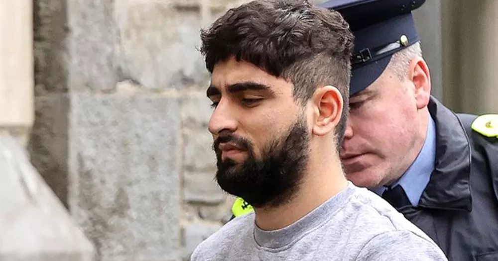 Yousef Palani, who was sentenced to life in prison for the murders of two men in Sligo. His side profile is shown from the shoulders up. He has dark hair and a beard, and a Garda is pictured behind him.