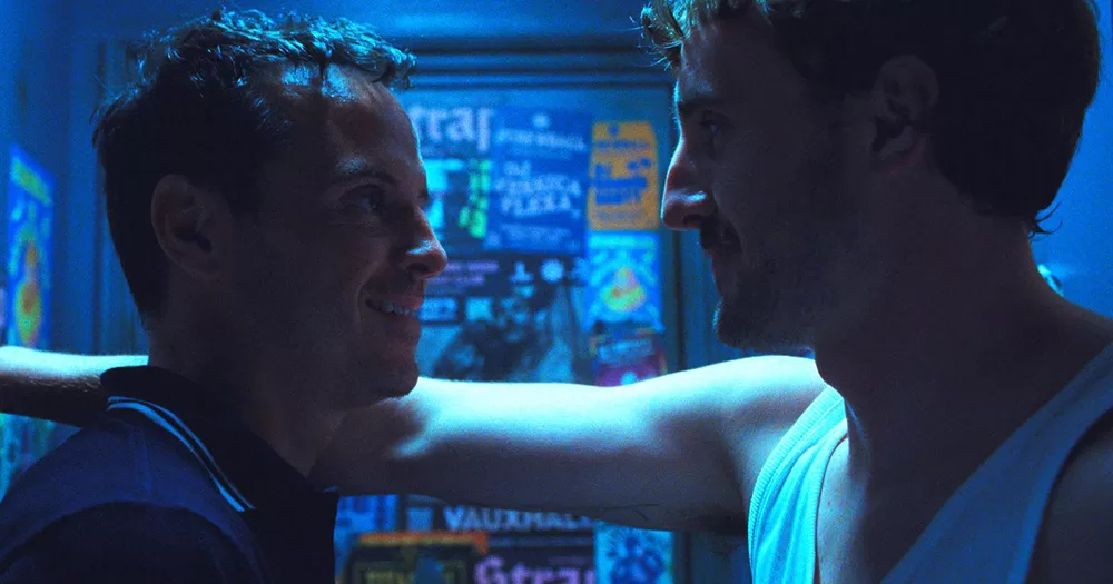A still of Andrew Scott and Paul Mescal. The pair filmed sex scenes together for All of Us Strangers. The image shows Scott on the left, smiling and looking at Mescal on the right, as they appear to be in a nightclub bathroom.