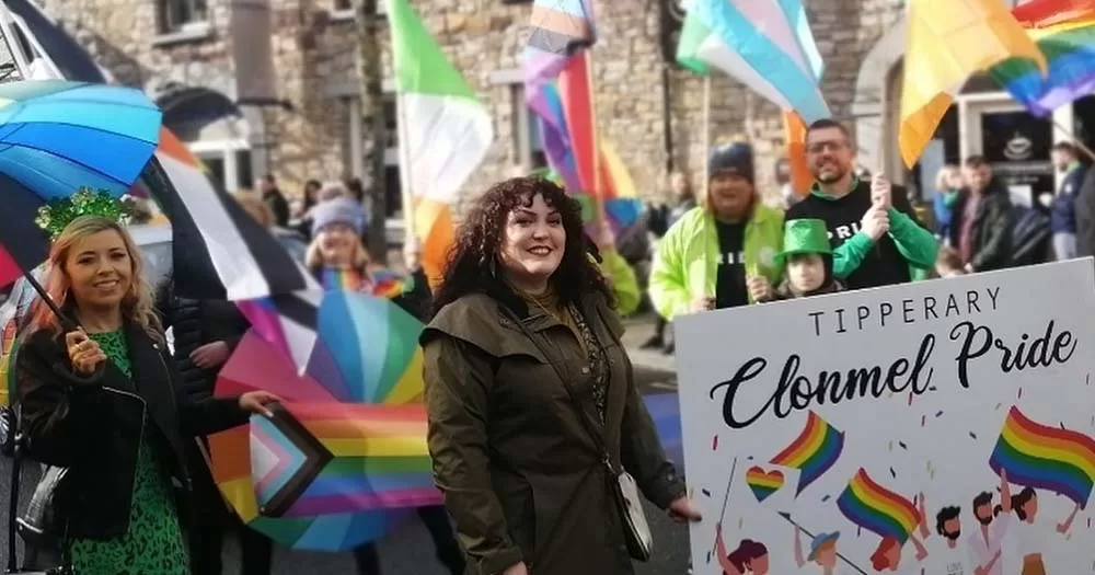 People marching with a banner and colourful Pride flags in the Clonmel Winter Pride festival