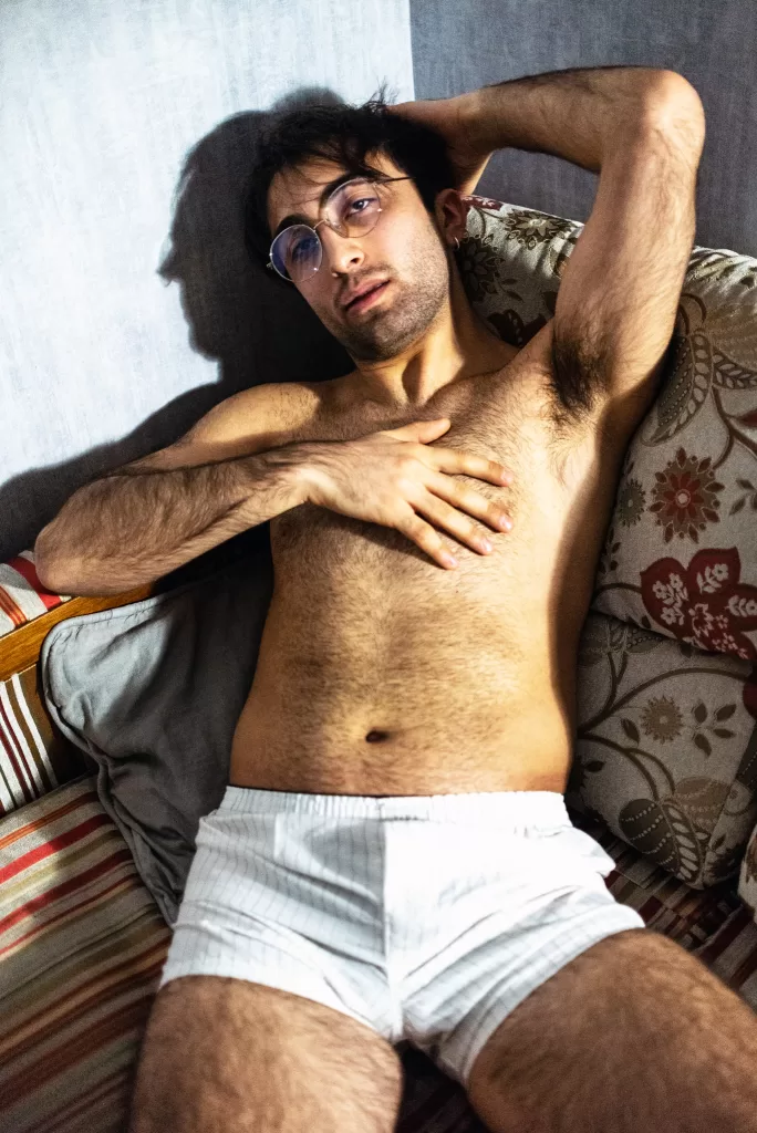 A photograph for Elska Tbilisi. A man is pictured wearing just white boxers. He lies on a chair with one arm behind his head and the other on his chest.