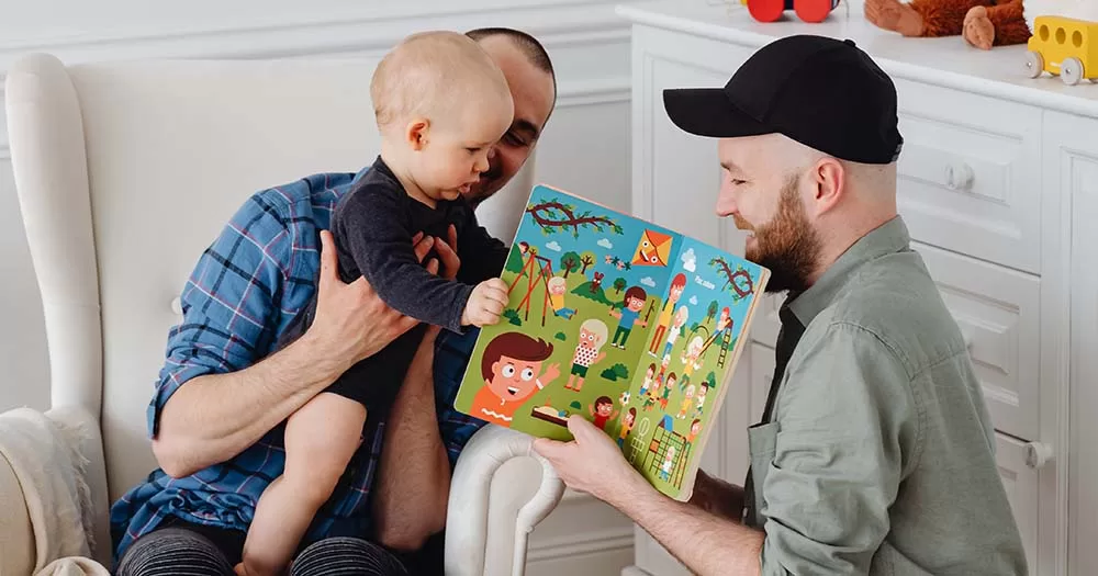Two parents read a book to a child representing the new Irish Gay Dads campaign