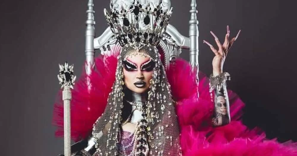 Pandora Nox sits on pink throne wearing drag make up, she became the first cis woman to win Drag Race!