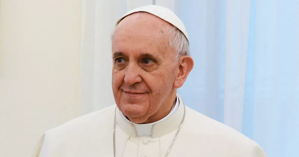 The story is about the Pope confirming trans people can be baptised in the Catholic church. The image shows Pope Francis from the shoulders up. He is looking off into the distance and smiling slightly.