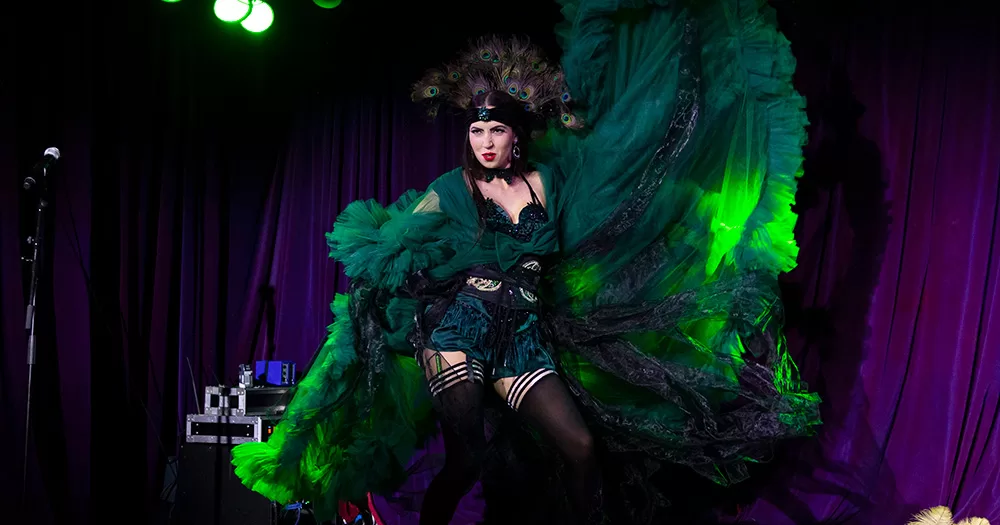 Image of a performer from the Candlelight Cabaret, which is holding its Christmas show this December. The burlesque dancer is wearing an extravagant green outfit.