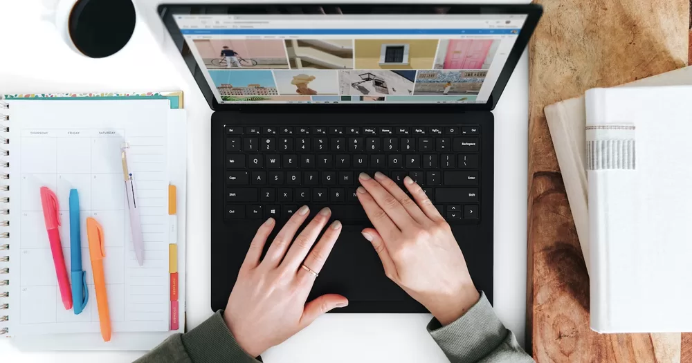 This article is about the GCN editor. In the photo, two hands working on a laptop with paper and colorful pens around.