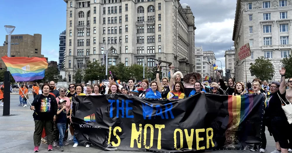This article is about LGBTQ+ rights in Ukraine and the EU. In the photo, a crowd at Kyiv Pride holding a banner that reads "The war is not over".