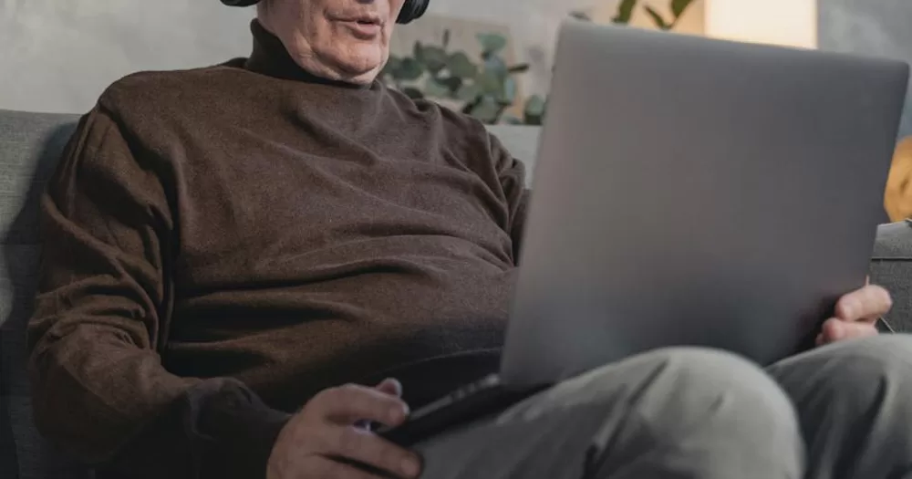 This article is about a survey on ageing within the LGBTQ+ community. In the photo, an older person with a laptop.