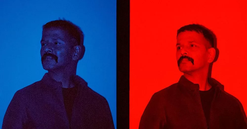 The image shows a split screen portrait of Pradeep Mahadeshwar who wrote a poem about racism in Ireland. The image shows two portraits of Pradeep. in both he is looking away to the left with his head slightly tilted upwards. The image on the left is saturated in Blue, the image on the right is saturated in red.