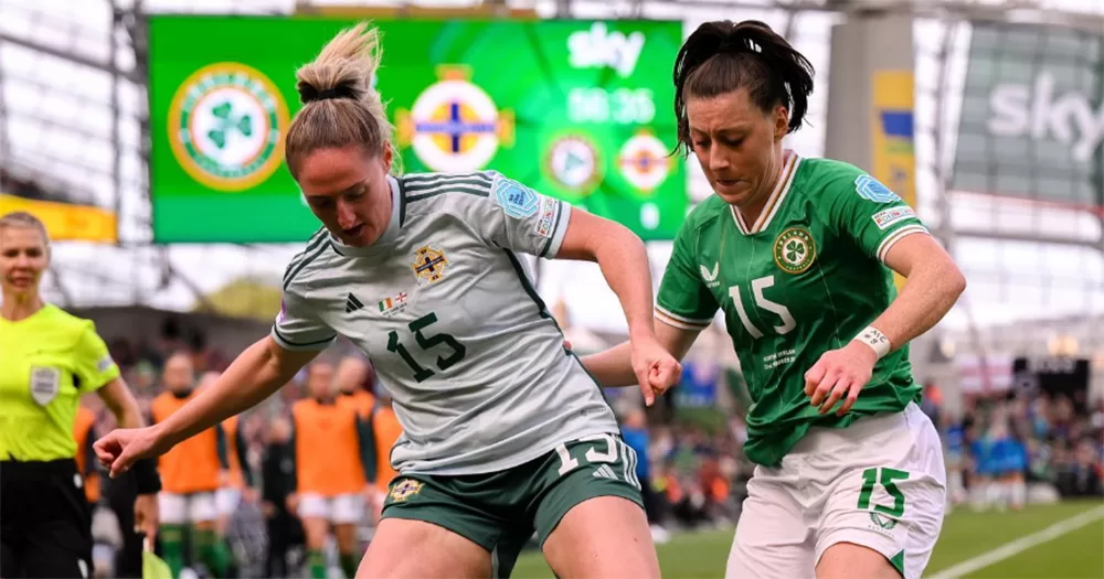 Rebecca Holloway and Lucy Quinn playing football against each other in the Aviva Stadium. Rebecca wears a Northern Ireland jersey, while Lucy wears a Republic of Ireland jersey.