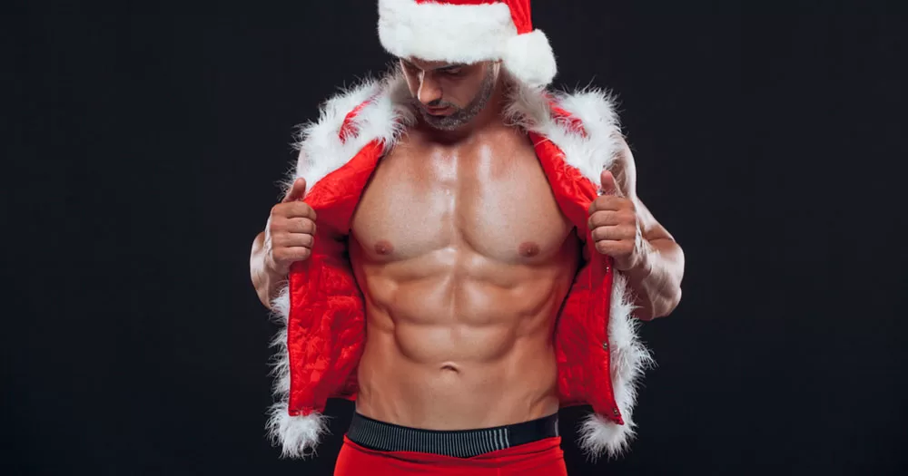 Squirt.org have launched fabulous Christmas giveaway. The image shows a man dressed in a Santa costume. He has the jacket open to reveal a bear chest with chiseled abs. His looking down at his muscles.