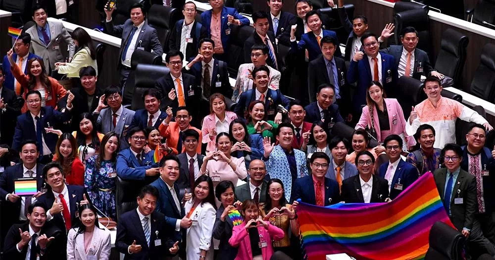 Crowd of legislators in Thailand pose with Pride flag representing bills for same-sex marriage