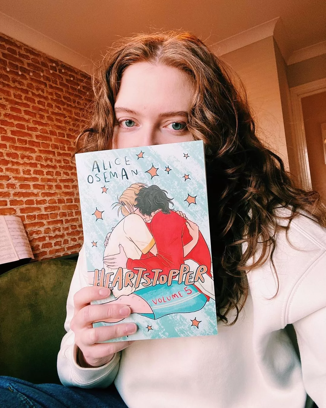 Photograph of Alice Oseman, one of the asexual celebrities listed in the article, holding a copy of Heartstopper