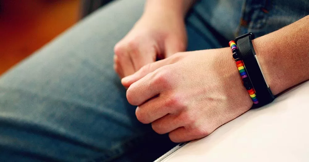Photograph of person's wrist wearing rainbow pride bracelet representing an LGBTQ+ ally