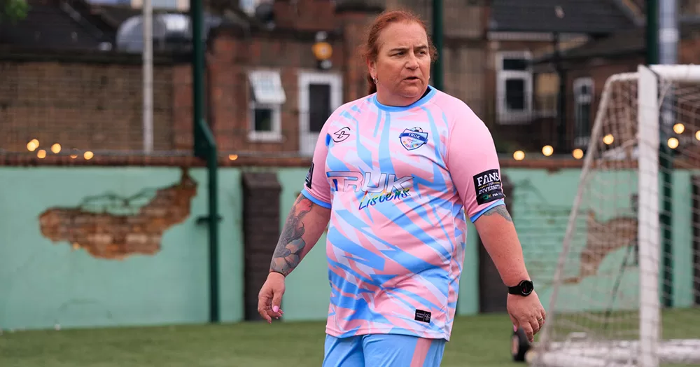 Lucy Clark playing football with TRUK United. She is photographed from the waist up, wearing a blue and pink football kit.