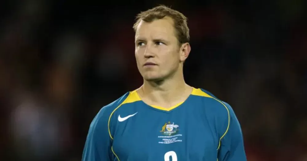 Stephen Laybutt playing football for Australia. He is photographed from the chest up, wearing a teal Australia jersey. He looks off into the distance.