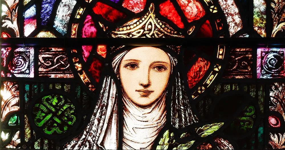 A stained glass portrait of St Brigid in multiple colours.