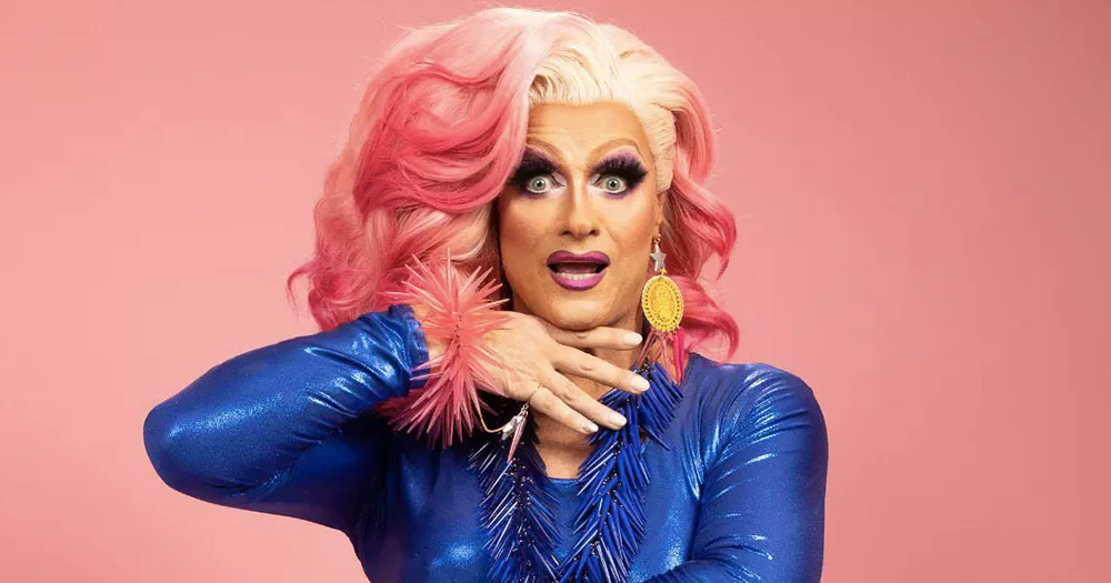 Panti Bliss, who will be Grand Marshal for St Patrick's Parade in Londo, wearing a blue dress, a pink and white wig on a pink background.