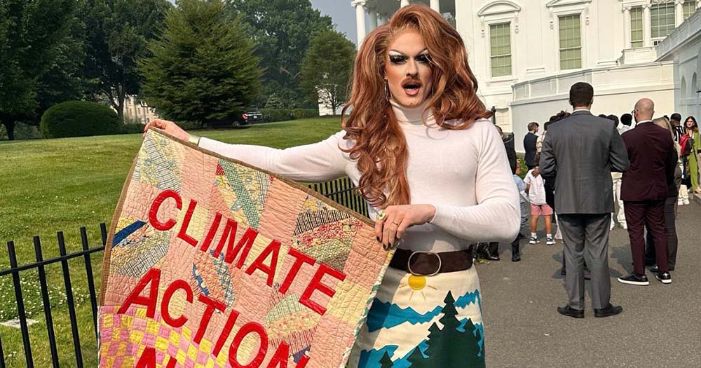 Photo of drag queen Pattie Gonia posing with a Climate Action sign, she was named one of the National Geographic travellers of the year.