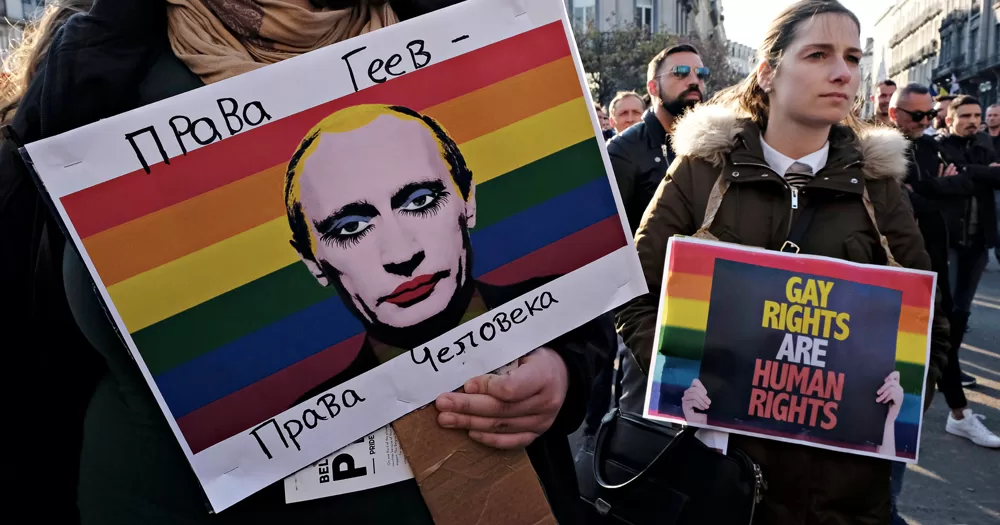 This article is about Russia handing out convictions after banning the LGBTQ+ movement. In the photo, protesters carrying signs with the rainbow flag.