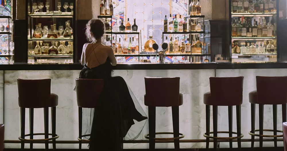 This article is about a new trans-exclusionary lesbian bar in London. The image shows the back of a woman sitting alone at a bar.