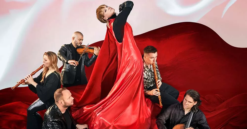 Photograph of Wallis Bird wearing red and posing with orchestra