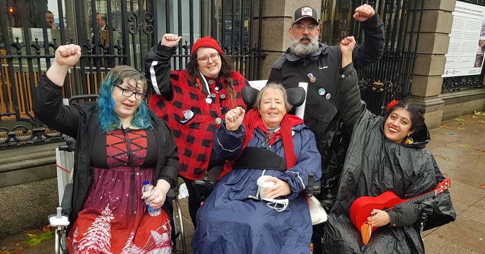 Photo of disability rights activists at a rally in Dublin, posing with their fists in the air