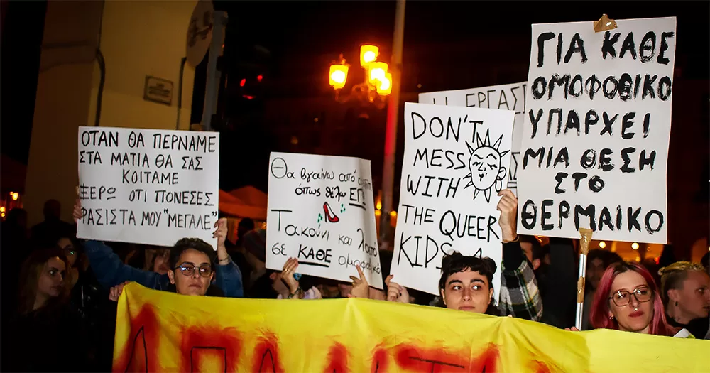 The picture shows protestors holding signs as they march in solidarity with the transgender couple attacked in Greece.