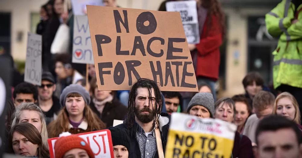 This article is about a Fianna Fáil TD calling for the abandonment of the hate speech bill. The photo is of protestors marching with a sign reading "No place for hate" in focus.