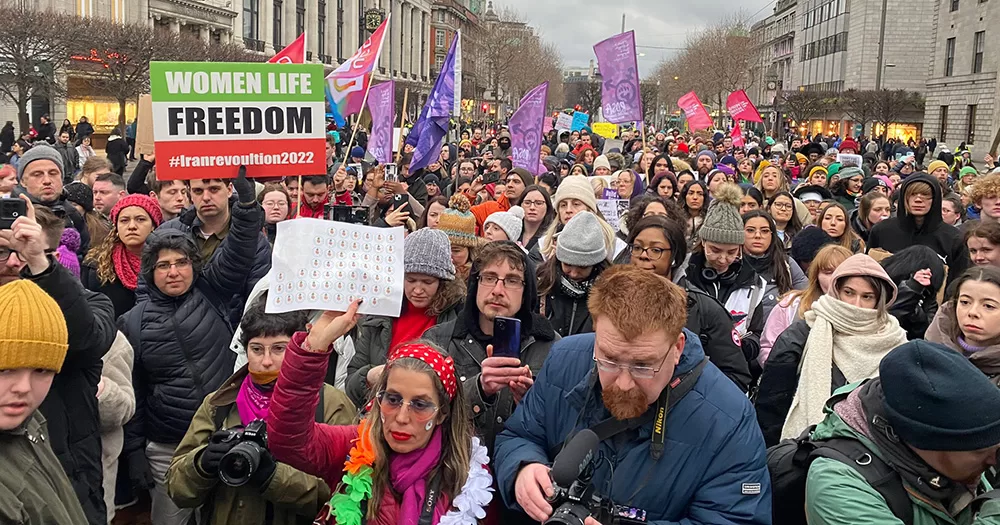 An image from the 2023 International Women's Day march. It shows a large ground of people marching through the streets of Dublin holding signs and flags.